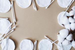 tampons de coton fleur de coton moelleux et cotons-tiges sur fond beige avec espace de copie. produit jetable hygiénique photo