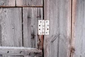 vieille charnière sur une porte de grange en bois avec des clous rouillés qui sortent des planches à la campagne. fond abstrait. photo