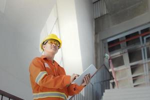 ingénieur ou contremaître tenant une tablette. site d'ingénierie des détails du travail et travail avec le concept technologique. photo