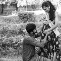 couple indien posant pour une séance photo de maternité. le couple pose dans une pelouse avec de l'herbe verte et la femme étale sa bosse de bébé dans le jardin de lodhi à new delhi, inde - noir et blanc