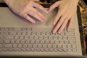 femme travaillant au bureau à domicile, mains sur le clavier de l'ordinateur portable. fermer photo