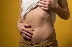 femme a soulevé un t-shirt blanc pour révéler un ventre mince avec un nombril. concept d'un mode de vie sain et d'une bonne nutrition. photo