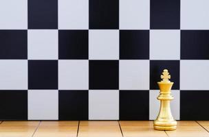 pièce d'échecs du roi d'or sur l'échiquier en bois photo