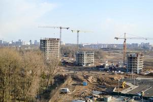 vue de dessus d'un grand chantier de construction avec des grues et des maisons de bâtiments panneau de cadre monolithique en béton gratte-ciel à plusieurs étages de la grande ville de la métropole photo