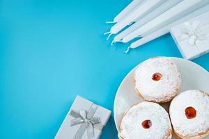 symboles de la fête religieuse juive hanukkah. dessert traditionnel beignets sufganiyot sur fond bleu. photo