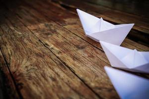 origami, bateau en papier blanc isolé sur un plancher en bois. les bateaux en papier signifient marcher. sentiment de liberté leadership photo