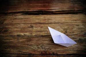 origami, bateau en papier blanc isolé sur un plancher en bois. les bateaux en papier signifient marcher. sentiment de liberté leadership photo