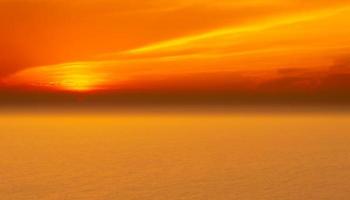 paysages marins de beau coucher de soleil sur la plage de la mer avec un ciel orange en vacances photo