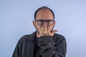 portrait d'homme barbu de 60 ans sur fond bleu avec chapeau et lunettes photo