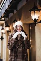 femme heureuse en manteau et chapeau marchant dans les rues de la ville photo