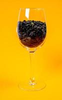 graines de tournesol noires dans un bocal en verre verre à vin. dans les graines de tournesol de seau sur fond jaune orange. graines de tournesol vue de face, photo