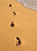 empreintes de pas sur la plage de sable doré. photo