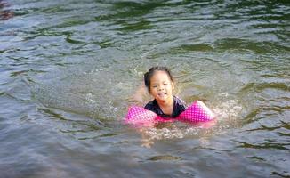 petite fille asiatique nageant dans la rivière photo