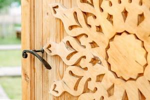 panneau en bois sur un fond en bois. porte en bois. portail en bois avec motifs. décor bois. poignée en fer sur la porte. style rustique à l'intérieur photo