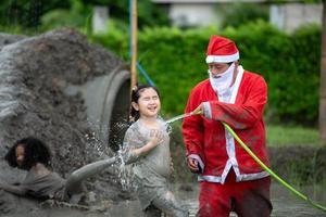 le gentil père noël aide à laver la boue qui se met sur le visage et les yeux des enfants photo