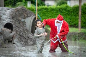 le gentil père noël aide à laver la boue qui se met sur le visage et les yeux des enfants photo