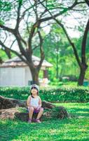 heureuse petite fille assise sur la racine de l'arbre dans le parc