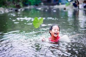 petite fille asiatique jouant dans l'eau avec feuille de lotus photo