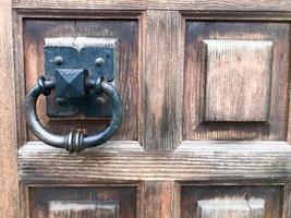 heurtoir de porte en métal noir, bouton de porte avec un anneau pour frapper sur le fond d'une vieille porte vintage en bois marron photo