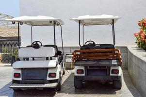 les voitures de golf électriques blanches sont garées dans de petits véhicules électriques avec des auvents du soleil dans un pays de villégiature exotique du sud tropical chaud photo