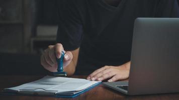 homme tamponnant l'approbation des documents bancaires de financement du travail ou de marketing d'investissement sur le bureau. photo