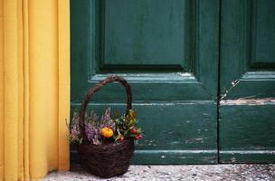 panier brun rempli de fleurs près de la porte colorée