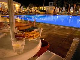 des parasols, des chaises longues et une piscine d'eau chaude et claire à l'hôtel tout compris la nuit dans une station balnéaire tropicale paradisiaque orientale photo