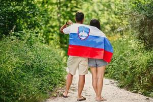 l'arrière du couple tient le drapeau slovène dans le parc national du triglav, en slovénie. photo