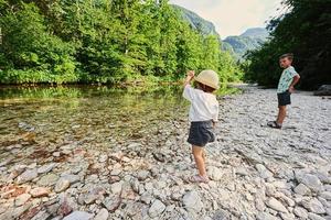 frère avec soeur sur la rive rocheuse d'une rivière calme dans le parc national du triglav, en slovénie. photo