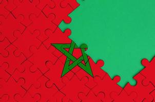 le drapeau du maroc est représenté sur un puzzle terminé avec un espace de copie vert gratuit sur le côté droit photo