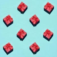 de nombreuses petites boîtes-cadeaux roses rouges sur fond de texture de papier de couleur bleu pastel à la mode dans un concept minimal. motif abstrait photo