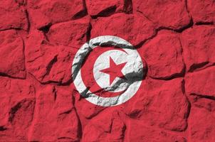 drapeau de la tunisie représenté dans des couleurs de peinture sur un vieux mur de pierre agrandi. bannière texturée sur fond de paroi rocheuse photo