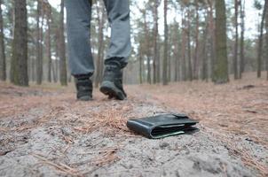 jeune homme perd son sac à main avec des billets en euros sur le chemin du bois de sapin d'automne russe. insouciance et perte de concept de portefeuille photo