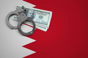 drapeau de bahreïn avec des menottes et un paquet de dollars. le concept d'enfreindre la loi et les crimes de voleurs photo