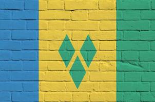 drapeau de saint-vincent-et-les grenadines représenté dans des couleurs de peinture sur un vieux mur de briques. bannière texturée sur fond de maçonnerie de gros mur de briques photo