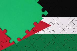 le drapeau de la jordanie est représenté sur un puzzle terminé avec un espace de copie vert gratuit sur le côté gauche photo