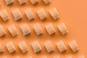 rouleaux de philadelphie au saumon sur fond orange. vue de dessus du minimalisme motif plat avec de la nourriture japonaise photo