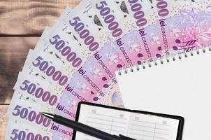 Éventail de billets de 50 000 leu roumains et bloc-notes avec carnet de contacts et stylo noir. concept de planification financière et de stratégie d'entreprise photo