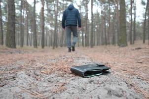 jeune homme perd son sac à main avec des billets en euros sur le chemin du bois de sapin d'automne russe. insouciance et perte de concept de portefeuille photo