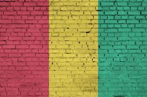 Le drapeau de la Guinée est peint sur un vieux mur de briques photo