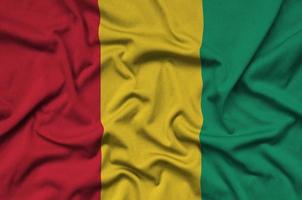 le drapeau de la guinée est représenté sur un tissu de sport avec de nombreux plis. bannière de l'équipe sportive photo