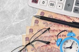 Billets de 10 roupies indiennes et calculatrice avec lunettes et stylo. prêt commercial ou concept de saison de paiement des impôts. le temps de payer les impôts photo