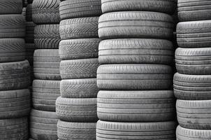 Vieux pneus usagés empilés avec des pieux élevés dans le garage de l'atelier de pièces de voiture secondaire photo