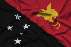 Le drapeau de la Papouasie-Nouvelle-Guinée est représenté sur un tissu de sport avec de nombreux plis. bannière de l'équipe sportive photo