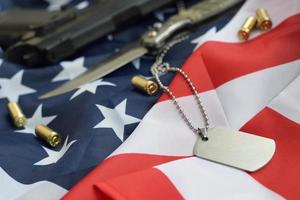 jeton d'étiquette de chien de l'armée avec des balles de 9 mm et un pistolet se trouvent sur le drapeau des états-unis plié photo