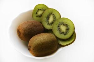 kiwis frais et juteux, hachés et entiers sur une assiette blanche. délicieux fruits et morceaux de kiwi vert. photo