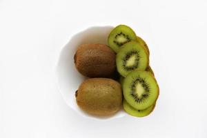 kiwis frais et juteux, hachés et entiers sur une assiette blanche. délicieux fruits et morceaux de kiwi vert. photo