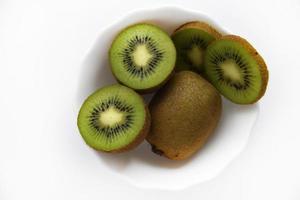 kiwis frais et juteux, hachés et entiers sur une assiette blanche. délicieux fruits et morceaux de kiwi vert. photo