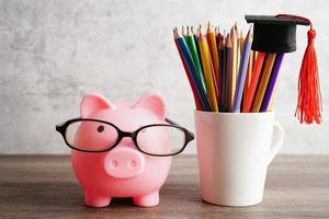 tirelire portant des lunettes avec des pièces de monnaie et une calculatrice économisant le concept d'éducation bancaire. photo