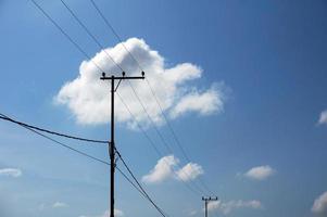 lignes électriques de poteau électrique fils électriques sortants contre le ciel bleu nuageux. photo